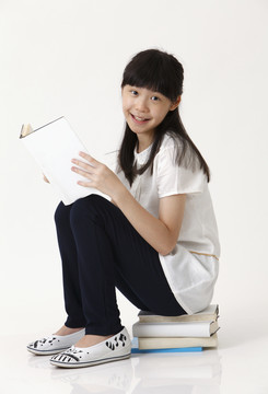 中国女孩坐在书上看照相机