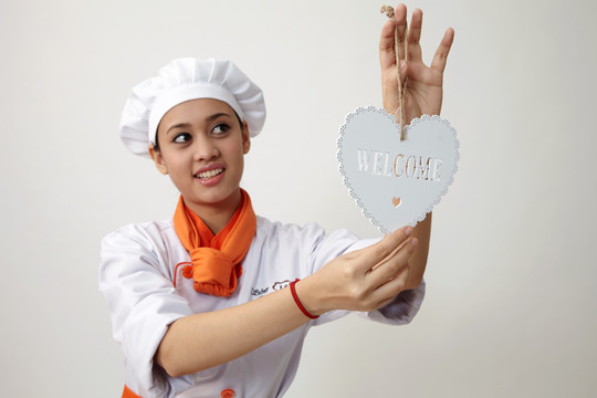 身着厨师制服手持欢迎标志的印度妇女