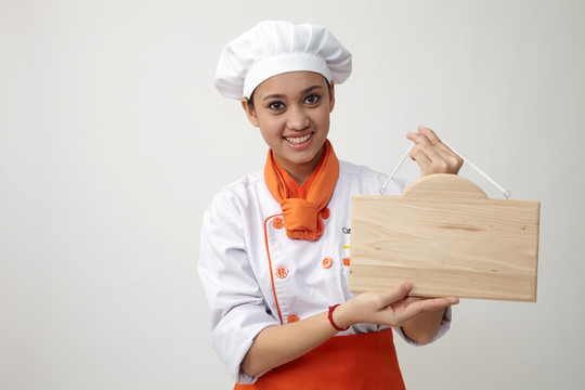 穿着厨师制服的印度女人拿着一块木板