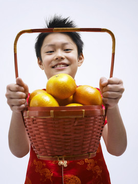 男孩举起装满桔子的篮子