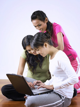 三个年轻女人一起使用笔记本电脑的照片