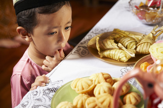 马来小男孩迫不及待地想吃桌上的食物