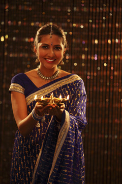 一个拿着油灯的穿着蓝色纱丽的印度女人