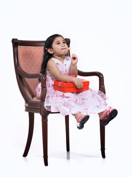 小女孩坐在椅子上吃糖果