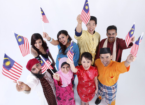 一群人举着马来西亚国旗，对着镜头摆姿势