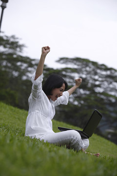快乐的年轻女子在户外使用笔记本电脑