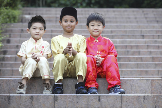 三个穿着传统服装的男孩坐在户外