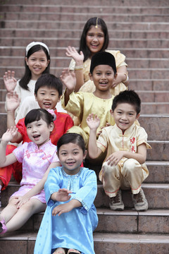 穿着传统服装坐在公园楼梯上的多种族儿童