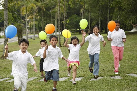 孩子们拿着气球在公园里跑