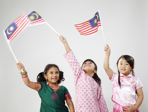 三个穿着传统服装手持国旗的女孩的剪影