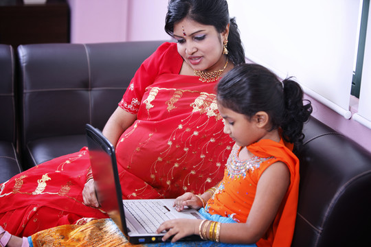孕妇带着女儿用笔记本电脑