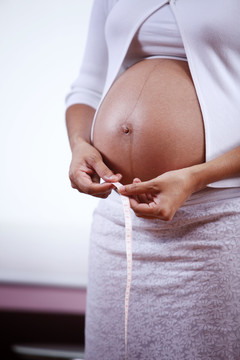 一位孕妇测量大肚子的特写镜头。