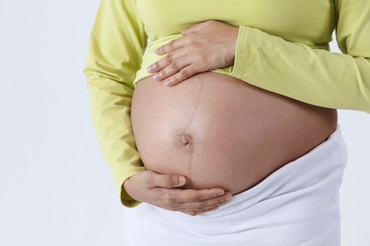 孕妇用手触摸腹部的画面。