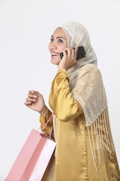 一名马来妇女拿着购物袋打电话。