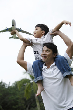 儿子抱着飞机坐在父亲肩上