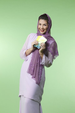 一名马来妇女手持绿包，身穿八柱裤