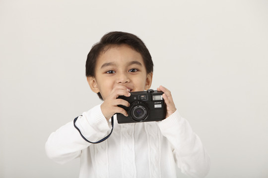 年轻的马来男孩拿着相机看着相机