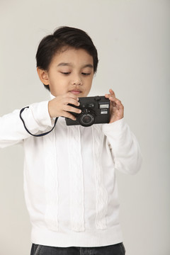 年轻的马来男孩拿着相机检查图像