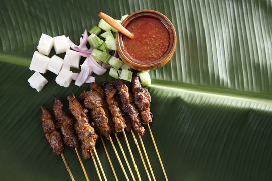 马来西亚食物沙爹的俯视图，香蕉叶上有黄瓜、洋葱和烤羊肉