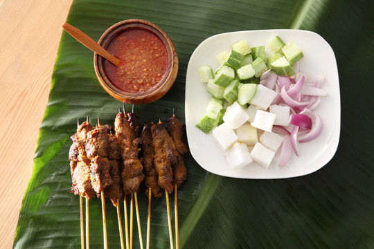 马来西亚食物沙爹的俯视图，香蕉叶上有黄瓜、洋葱和烤羊肉