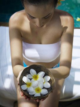 顶角是一个女孩拿着一个装满鲜花的椰子水碗漂浮在上面