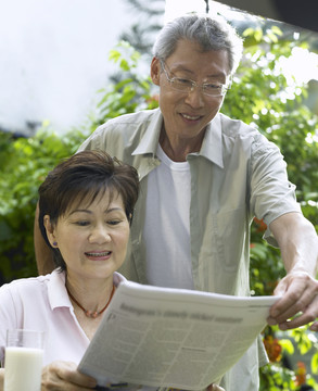 一对夫妇在花园里看报纸