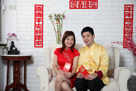 一对中国夫妇坐在沙发上用中国的新年装饰致意