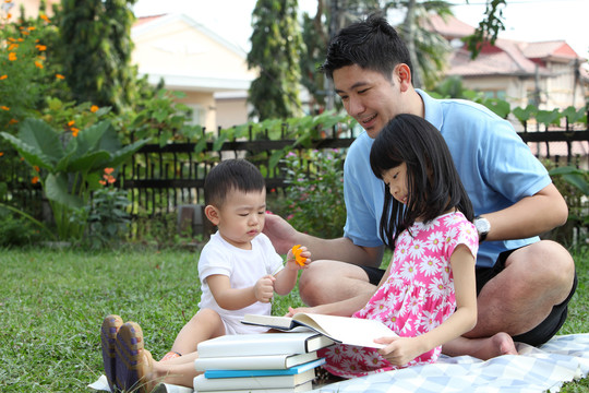 快乐的中国家庭在他们的花园里读书