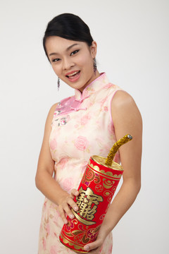微笑的中国女人穿着传统旗袍手持大爆竹