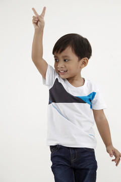 马来男孩站着举起手臂，手举和平手势
