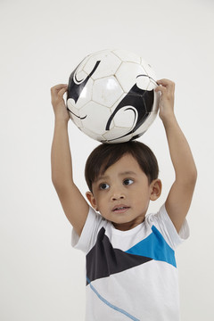 马来男孩在玩足球