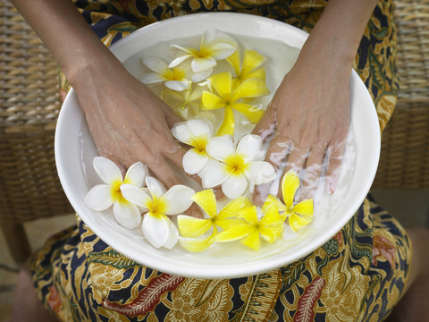 一个女人把手浸在一碗花水里