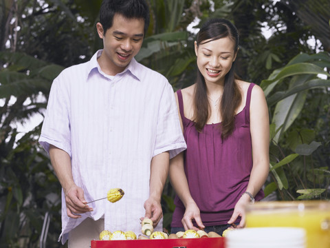 女人和男人微笑着为聚会准备食物