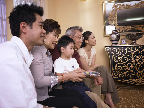一家人一起看电视的侧面照片