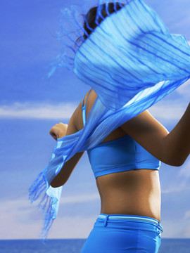 风吹拂沙滩上戴着围巾的女人的侧面照片