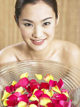 亚洲女孩举着一盘玫瑰花瓣