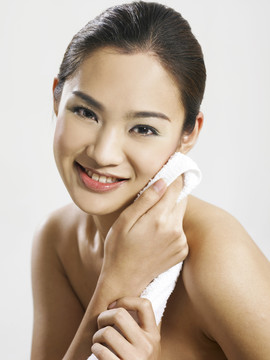 亚洲女性用毛巾擦脸，微笑着