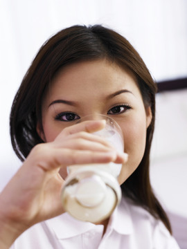 喝健康牛奶的年轻女子的正面图