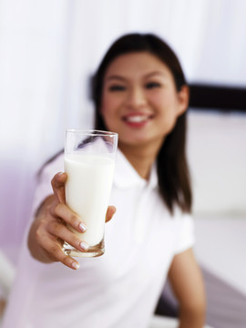 一位年轻女士拿着一杯牛奶