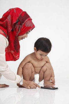 一位马来妇女带着她的儿子玩这个现代化的小玩意儿