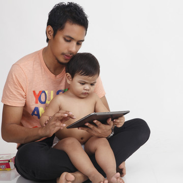 马来人的父亲和他的儿子拿着一个数字平板电脑