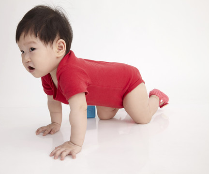 在白色背景上爬行的中国婴儿