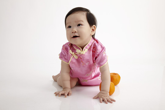 穿着旗袍在白色背景上爬行的中国婴儿