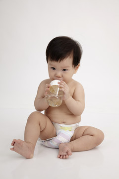 中国女婴抱着奶瓶里的水坐着