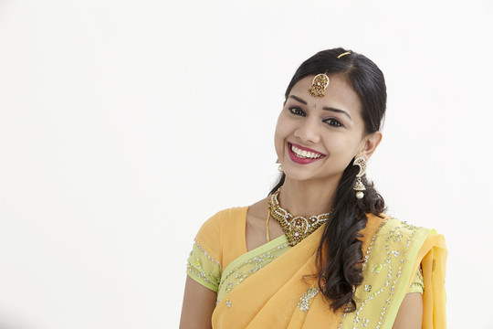 一位美丽的印度年轻女子的面部特写肖像，她热情友好的微笑