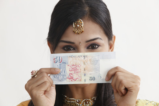 一个穿着纱丽的妇女手里拿着新加坡的钞票