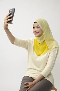 马来女子手持智能手机自拍