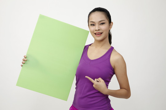 一位穿着运动服的中国年轻女子，白色背景上有一块空白的白板。是时候健身了。