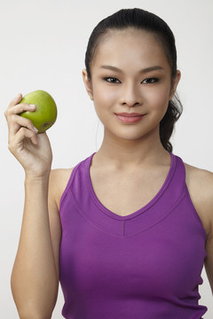 健康漂亮的中国白衣女孩手里拿着一个青苹果