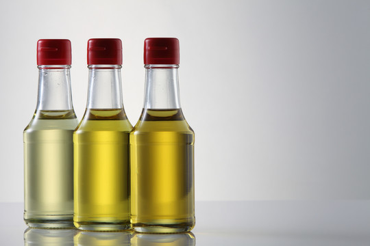 芝麻籽油、橄榄油、葡萄籽油和玉米油装在白色背景的玻璃瓶中